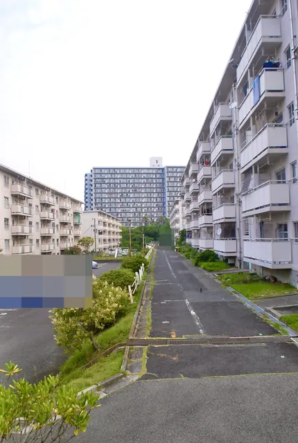 団地と駐車場のあいだを、奥の高層住宅へ上る細い坂道