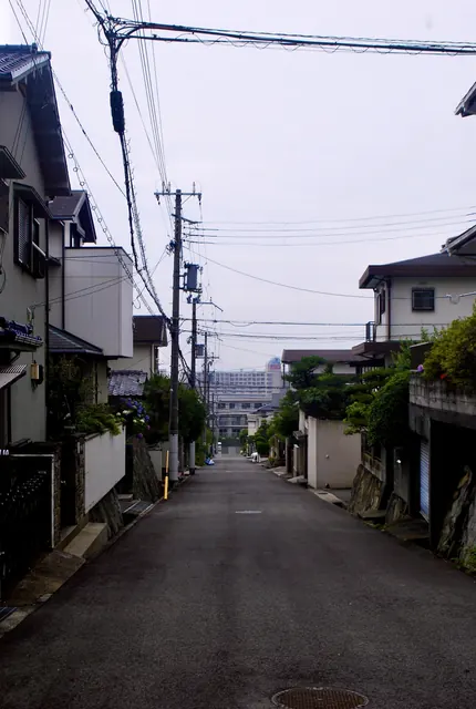 電柱と家々が並び、奥の建物までまっすぐ続く坂道