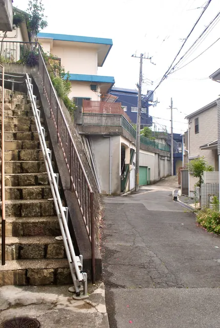 手すりのついた石の階段が、家の脇を上へ続く風景