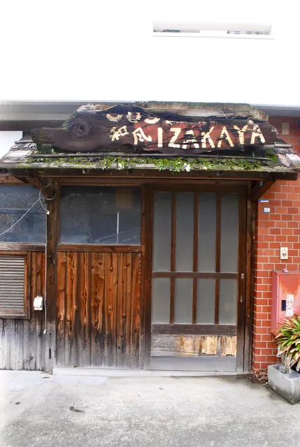 木彫りの看板と木の扉の、昔ながらの居酒屋の店先