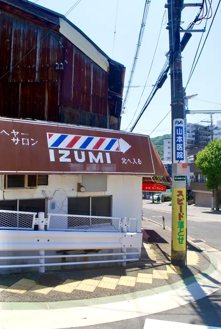 サインポール柄の大きな看板と、トタン壁の古い建物
