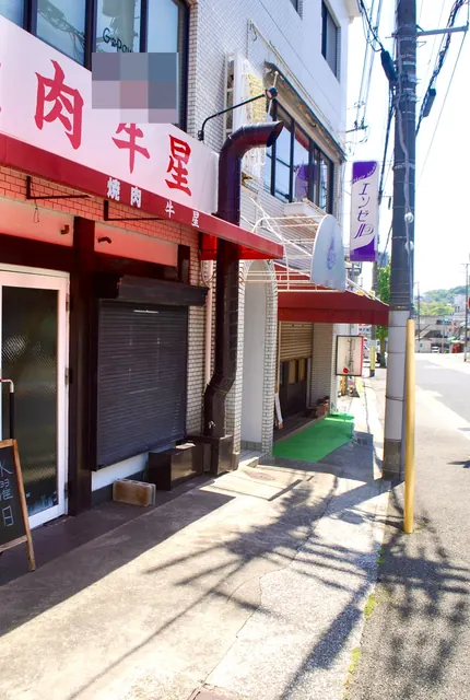 赤い日よけの焼肉店と縦長の看板の美容室が並ぶ通り