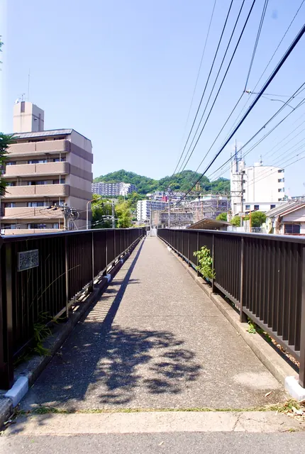 陸橋の上の歩道から、町並みと山並みを見渡す風景
