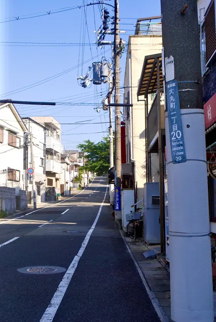 町名表示のある電柱の脇から、奥へ上っていく住宅街の坂道