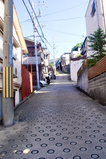 丸い滑り止めの模様が続く、家々のあいだの坂の路地