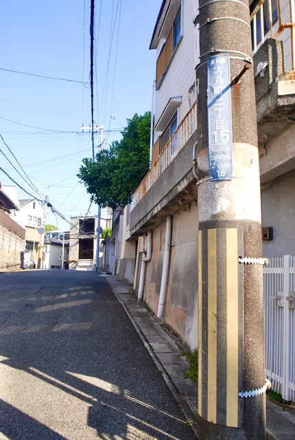 電柱と家々に挟まれ、下っていく住宅街の坂道