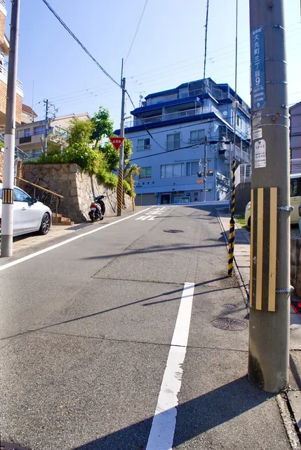 大きな電柱の立つ、坂の上の交差点