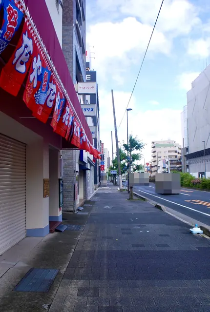 赤いのぼりが並ぶ店先から、街路樹の続く大通りの歩道
