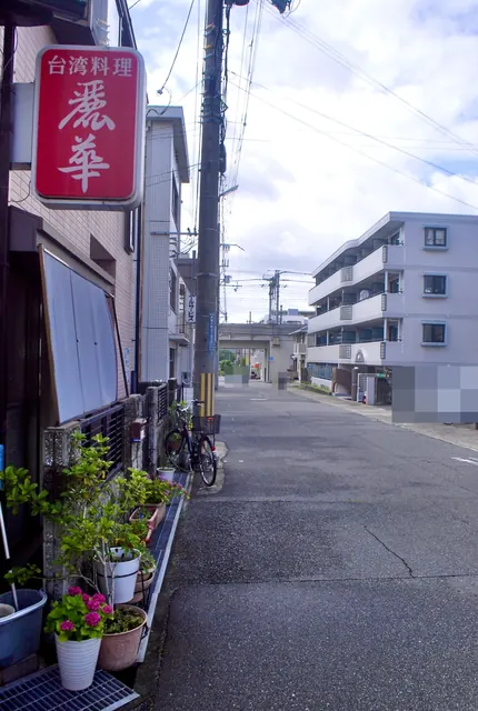 赤い「台湾料理 麗華」の看板の先に、高架の線路へ続く道
