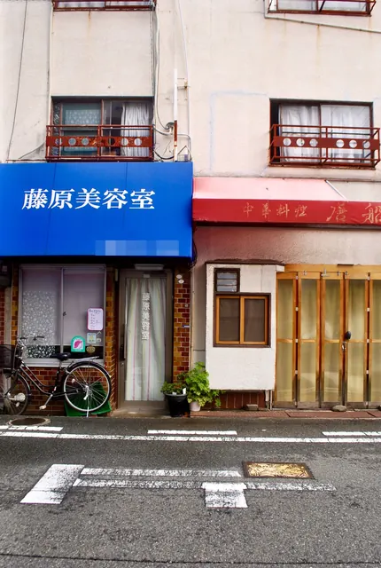 青い日よけの藤原美容室と、木の格子戸が並ぶ中華料理の店先