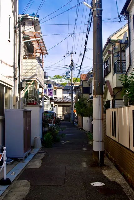 電柱が立つ細い路地。奥に瓦屋根の家が見える