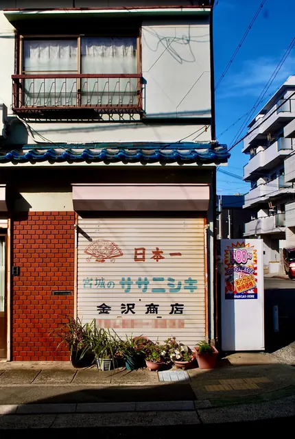 手描き風の文字が残るシャッターとレンガ壁の店先