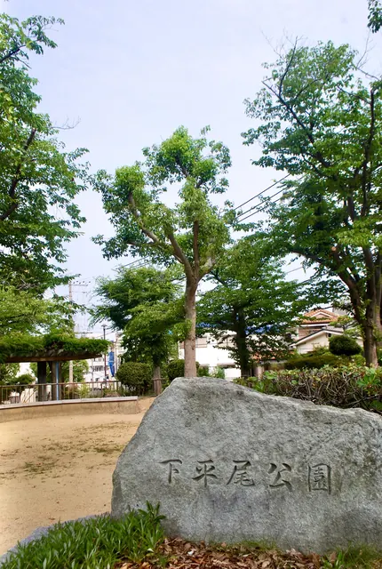 「下平尾公園」と刻まれた大きな石と、木々に囲まれた広場