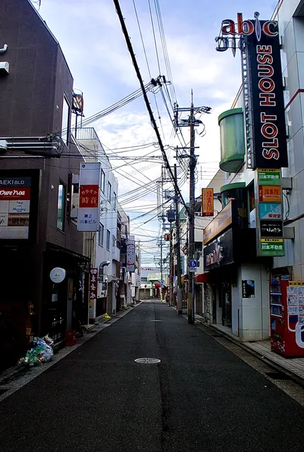 大きな縦長の看板と電柱が並び、奥へ続く駅前の通り