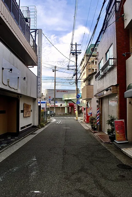 サインポールの理容店の先に、歩道橋と交差点が見える通り