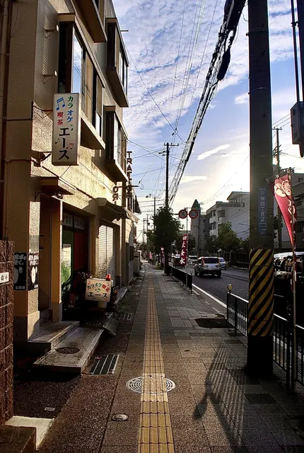 カラオケ喫茶の看板が出た建物と、夕方の光が差す歩道