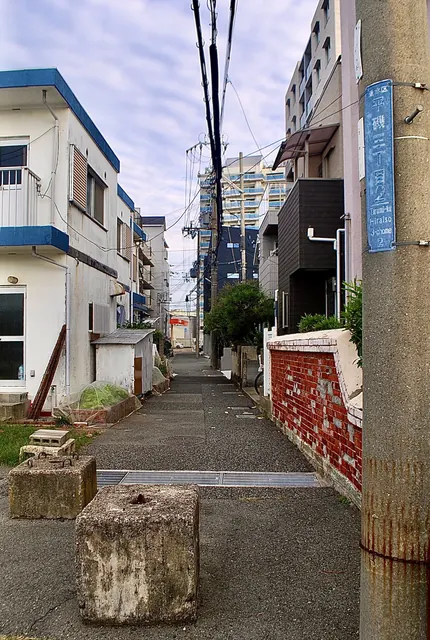 町名表示のある電柱の脇を、奥へ続く細い路地