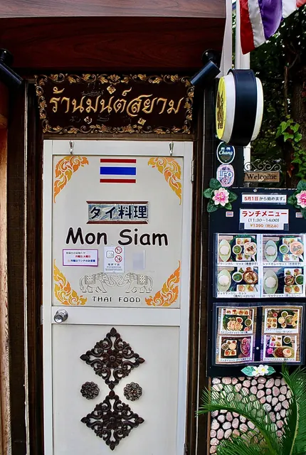 金色の飾り看板と、象の絵が描かれた白い扉のタイ料理店