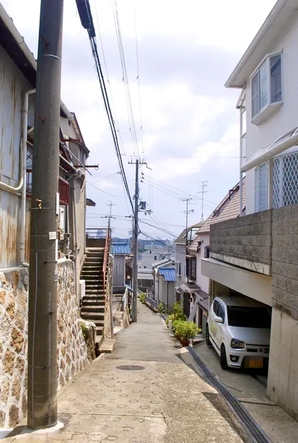 石垣の脇の階段と、遠くの町並みへ下っていく坂道