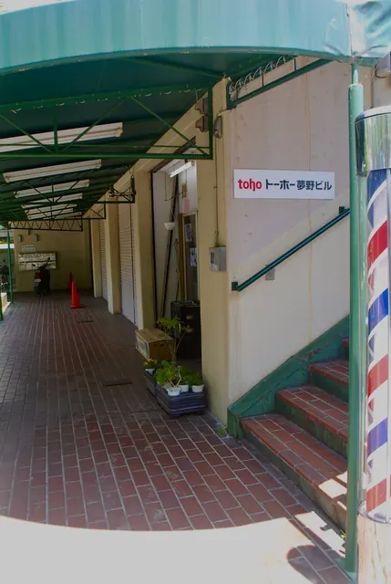 緑の屋根のアーケードと、サインポールのある店先
