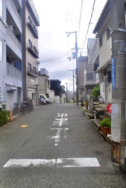 電柱と家々が並び、坂の上へまっすぐ続く住宅街の道