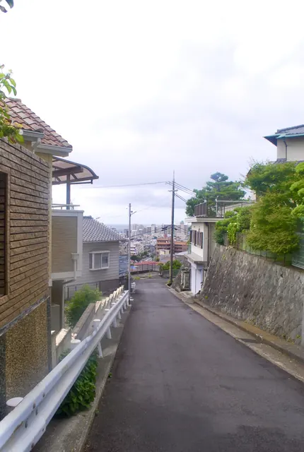 ガードレールに沿って、遠くの街並みと海へ下っていく坂道