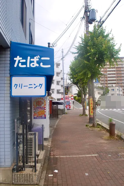青い「たばこ」の看板と、並木の続く大通り沿いの歩道