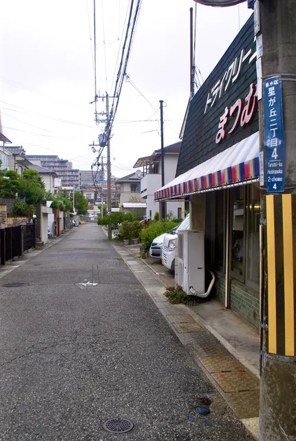赤白青のしましまの日よけの店先から、まっすぐ続く道