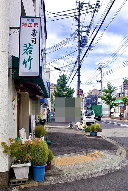 「寿司 若竹」の縦看板と、植木の並ぶ交差点の角