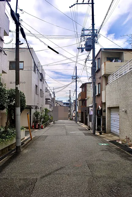 電柱と家々のあいだを、奥までまっすぐ続く住宅街の道
