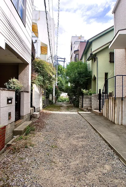 家々のあいだを、奥の緑へ続く砂利の細い路地