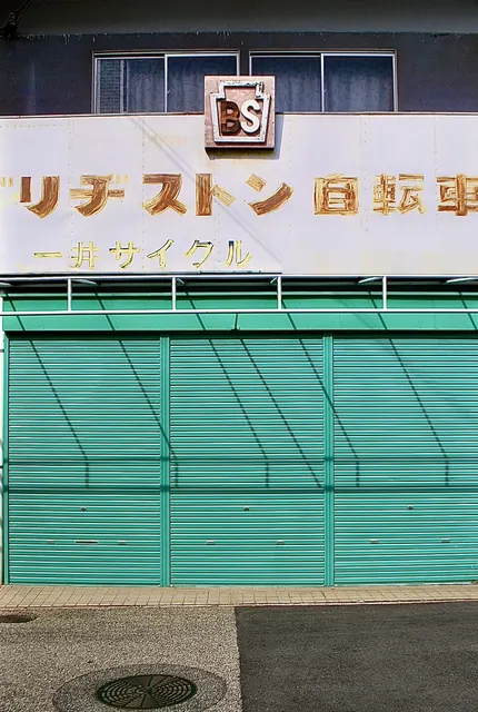 手書き風の「ブリヂストン自転車」の文字と、緑のシャッター