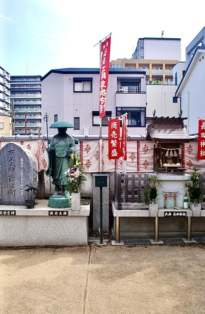 弘法大師の像と、「商売繁盛」ののぼりが立つ小さなお社