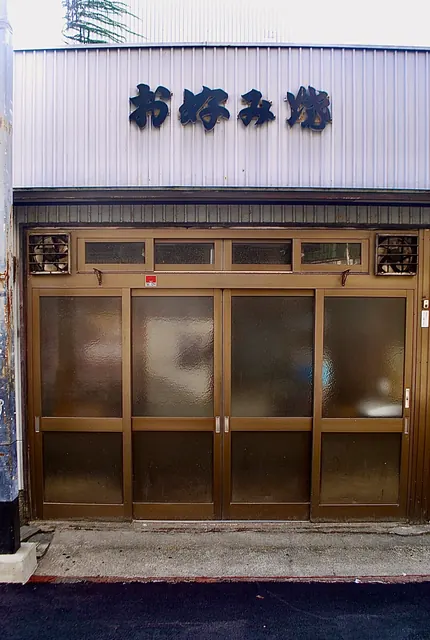 「お好み焼」の看板と、すりガラスの格子戸が並ぶ古い店先