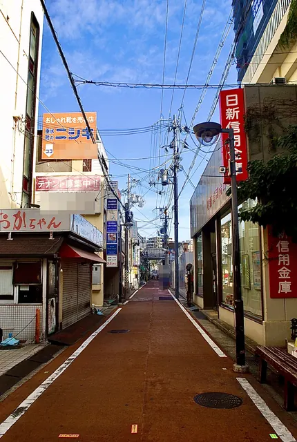 赤く塗られた細い通りの両側に、小さな店と看板が並ぶ風景