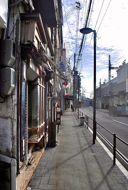 古い店の並ぶ歩道と、線路の高架に沿って続く道路