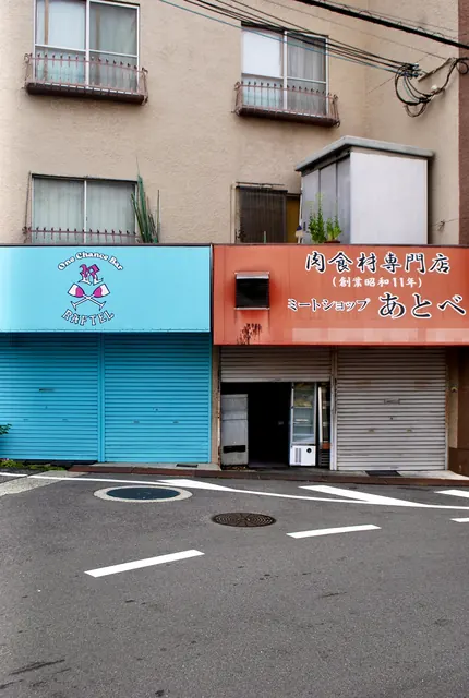 水色とオレンジのシャッターが並ぶ、昭和創業の精肉店の店先