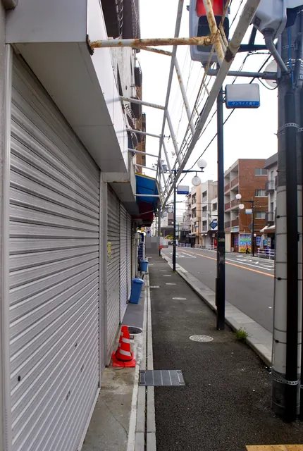 閉まったシャッターと電柱のあいだを、まっすぐ続く歩道