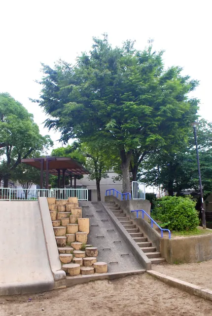 丸太を並べた階段とすべり台、あずまやのある公園