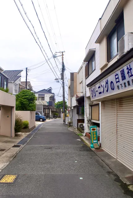 「クリーニングの白鵬社」の看板と、奥へ続く住宅街の道