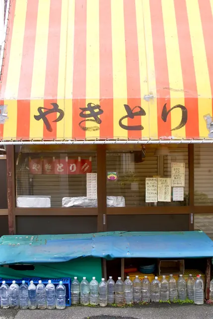 赤と黄色のしましまの日よけに「やきとり」と書かれた店先