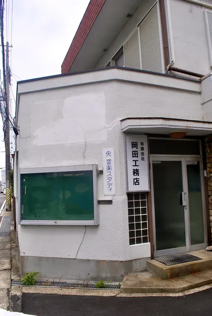 「岡田工務店」の看板と掲示板のある、古い建物の角
