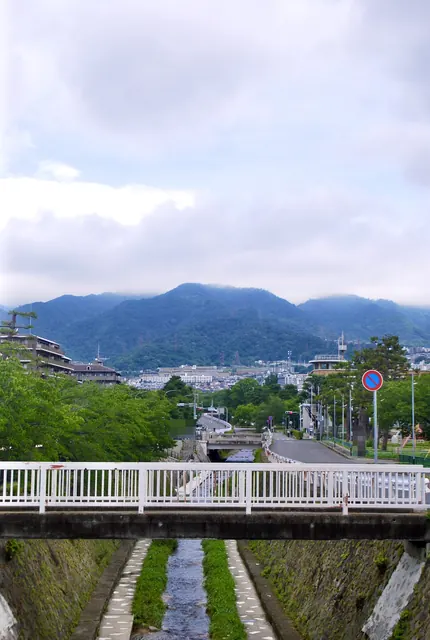 白い欄干の橋の上から、川と六甲山の山並みを望む風景
