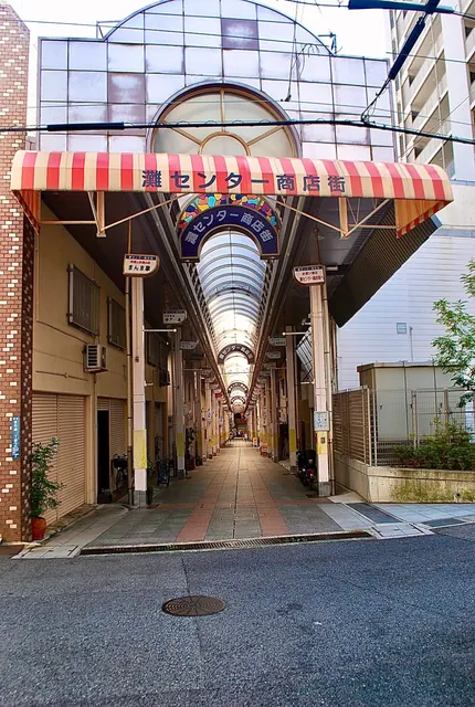 赤白の縞模様の日よけがかかる、商店街のアーケードの入口