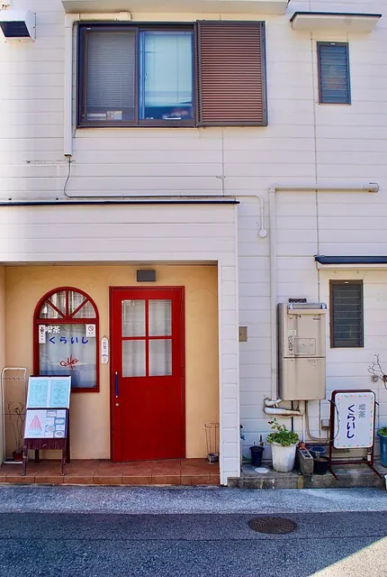 赤い扉とアーチ形の窓がある、白い外壁の建物の店先