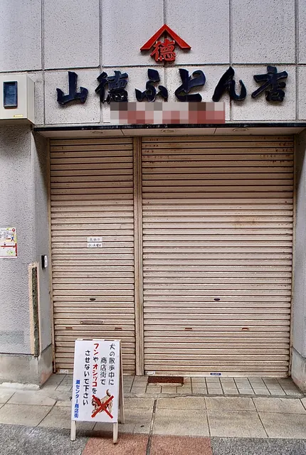 大きな文字の看板と、下りたシャッターのふとん店