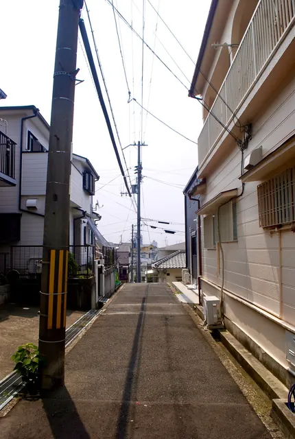 電柱と家々のあいだを、遠くの町へ下っていく坂道