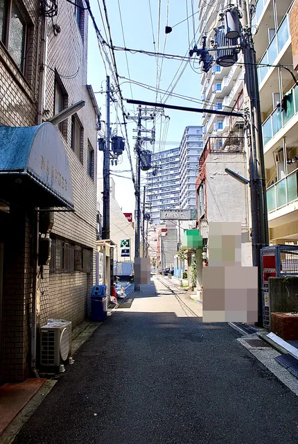 「世界長」の看板や居酒屋の看板が並ぶ、奥へ続く細い道