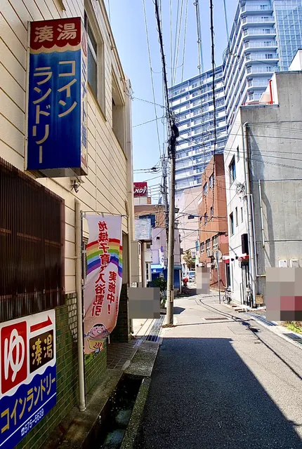 「湊湯」「コインランドリー」の青い看板のある、細い道