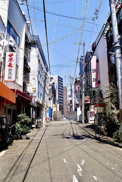 居酒屋の看板が並び、遠くの高層マンションまで続く通り